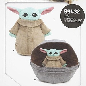 May include: A sewing pattern featuring a plush Grogu and soft space pram. The pattern includes a plush Grogu doll with a light green face, large ears, and a tan robe. The pram is gray and has a brown interior.