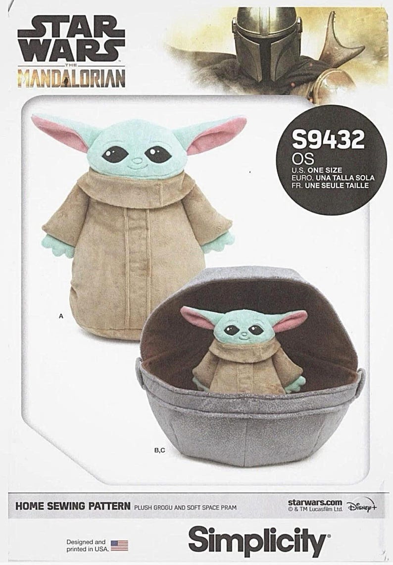 May include: A sewing pattern featuring a plush Grogu and soft space pram. The pattern includes a plush Grogu doll with a light green face, large ears, and a tan robe. The pram is gray and has a brown interior.