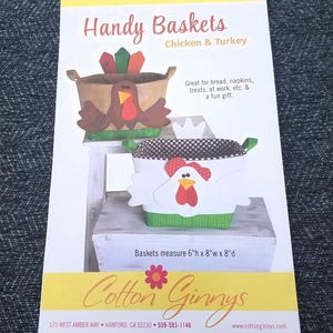 May include: Two decorative baskets with handles, one shaped like a turkey and the other like a chicken. The turkey basket is brown with a red and green accent. The chicken basket is white with a red and black checkered pattern. Baskets measure 6"h x 8"w x 8"d. The text "Handy Baskets" is at the top.