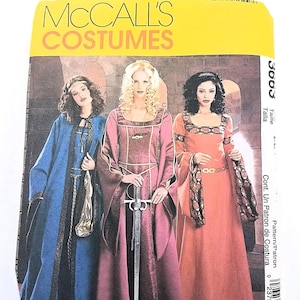 May include: A McCall's Costumes sewing pattern envelope, number 3663, featuring illustrations of three long-sleeved gowns with square necklines and decorative trim. The gowns are shown in blue, magenta, and orange, with one figure holding a sword.