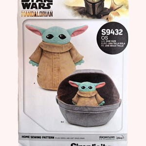 May include: A sewing pattern for a plush Grogu and soft space pram. The pattern features Grogu in a tan coat with large ears and a small plush Grogu in a gray pram. The Star Wars: The Mandalorian logo is at the top.