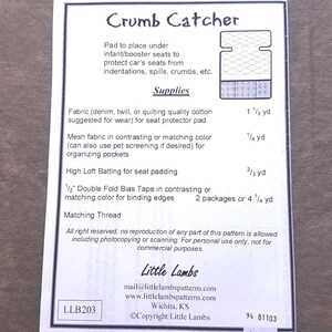 May include: A sewing pattern sheet titled Crumb Catcher for an infant or booster seat protector pad. It lists required supplies including fabric, mesh, batting, and bias tape with measurements in yards. Includes contact info for Little Lambs.