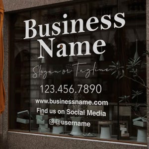 Könnte beinhalten: Ein Schaufenster mit einem weißen Schild, auf dem "Business Name", "Slogan or Tagline", "123.456.7890", "www.businessname.com", "Find us on Social Media" und "@username" steht.