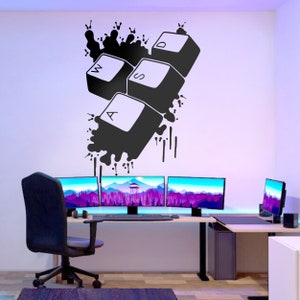 May include: Black and white keyboard keys with the letters W, A, S, and D, splattered with black paint, on a white wall with three computer monitors and a desk in the background.