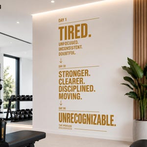 May include: A motivational wall decal in a gym setting. The text reads "Day 1: Tired, Unfocused, Inconsistent, Doubtful" transitioning to "Day 30: Stronger, Clearer, Disciplined, Moving" and finally "Day 90: Unrecognizable."