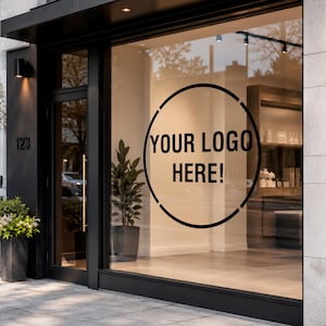 Puede incluir: Un escaparate con un adhesivo circular negro que muestra el texto YOUR LOGO HERE! en letras mayúsculas negritas. El cristal está enmarcado por una estructura de metal negro con una puerta a la izquierda y una planta visible tras el vidrio.