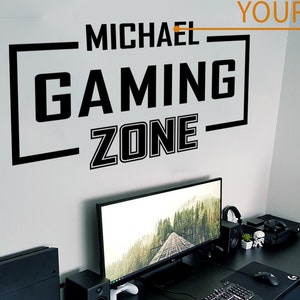 Könnte beinhalten: Ein schwarz-weißes Gaming-Zone-Schild mit dem Text "MICHAEL GAMING ZONE" und "YOUR NAME" an einer weißen Wand. Ein schwarzer Schreibtisch mit einem Computermonitor, einer Tastatur, einer Maus und einem Gaming-Stuhl.