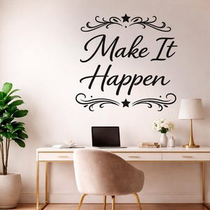 以下が含まれることがあります： 「Make It Happen」という文字が筆記体で書かれた黒いウォールステッカー。上下に装飾的な渦巻き模様と星があしらわれ、デスク、椅子、ランプ、鉢植えの植物が置かれた無地の壁に貼られている。