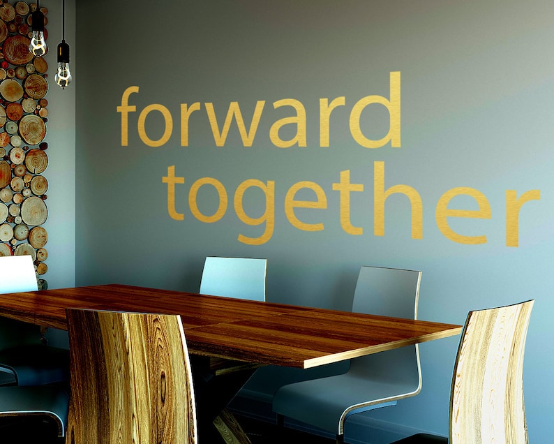 May include: A wooden table with four chairs in a room with a light grey wall. The wall has the words "forward together" written on it in gold lettering.