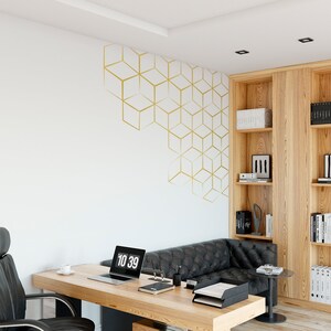 May include: A home office with a wooden desk, a black leather sofa, and a bookshelf. The wall has a gold geometric pattern. A laptop computer is on the desk with the time 10:39 displayed on the screen.