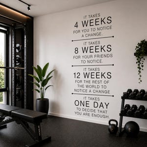 Può includere: Una palestra domestica con una panca pesi nera, un rack per pesi e manubri. Una citazione motivazionale è sul muro: "Ci vogliono 4 settimane per notare un cambiamento...un giorno per decidere che sei abbastanza."