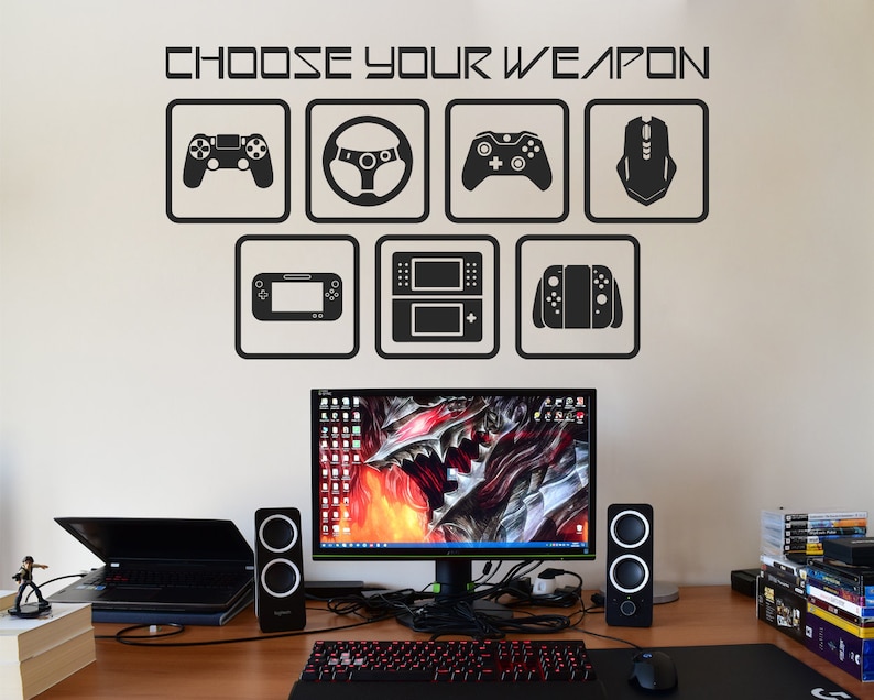 May include: A white wall with a black and white graphic that says "Choose Your Weapon" with icons of different gaming controllers, including a steering wheel, a game console, a joystick, and a mouse.