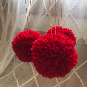 Set of three yarn pom tree ornaments hung from a gold string