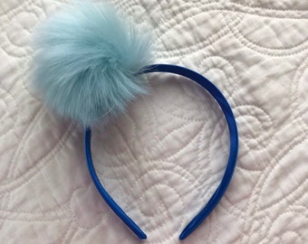 Light blue faux fur pom pom on deep blue satin covered headband