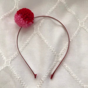 Red and pink yarn pom pom on red headband