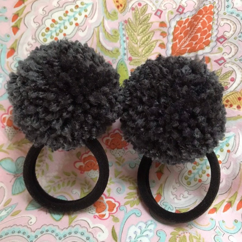 Set of two gray yarn pom pom hair ties on balck elastics