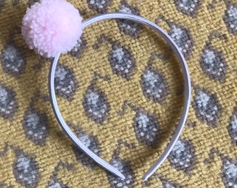 Light pink yarn pom pom on silver satin covered headband