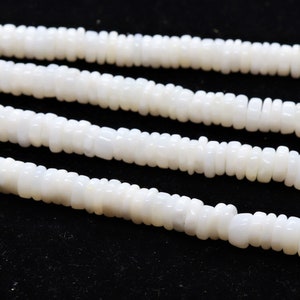 May include: A strand of white, opaque, round beads, strung together to form a necklace. The beads are slightly irregular in shape and have a matte finish.