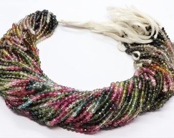 May include: A strand of multi-colored gemstone beads. The beads are round and have a variety of colors, including pink, green, blue, and black. The beads are strung on a white cord.