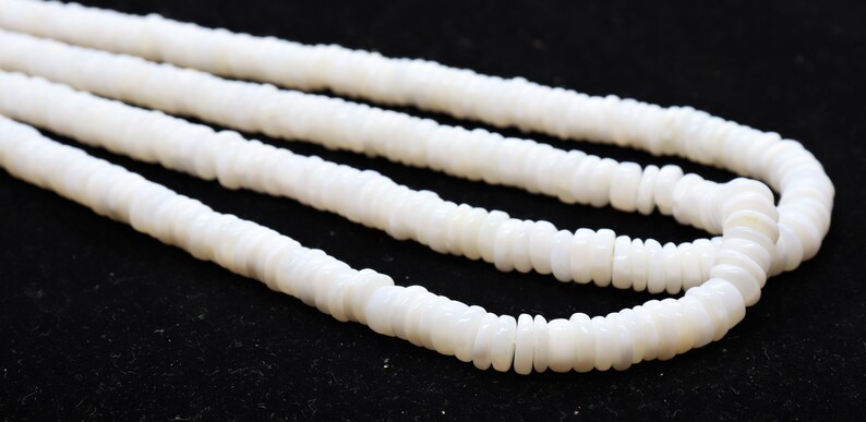 May include: A strand of white shell beads, with a smooth, polished finish. The beads are arranged in a circular pattern, creating a delicate and elegant look.