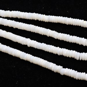 May include: A strand of white shell beads, with a smooth, polished finish. The beads are arranged in a long, continuous string, and they are all of a uniform size and shape.