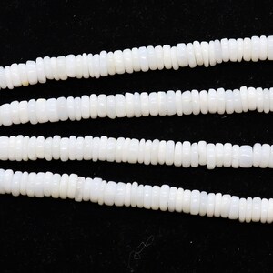 May include: A strand of white shell beads, with a smooth, matte finish. The beads are oval shaped and have a slightly irregular texture. The strand is approximately 18 inches long.