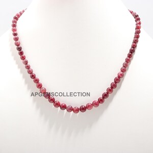 Puede incluir: Un collar de cuentas de piedras preciosas rojas. El collar está hecho de cuentas redondas y tiene aproximadamente 45 cm de largo.