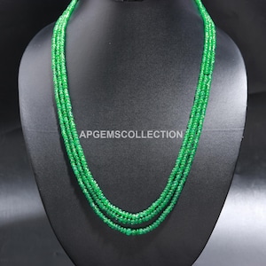 Peut inclure: Un collier à trois rangs composé de perles d'émeraude vertes. Le collier est présenté sur un buste de mannequin noir. Le texte "APGEMSCOLLECTION" est visible sur le buste.