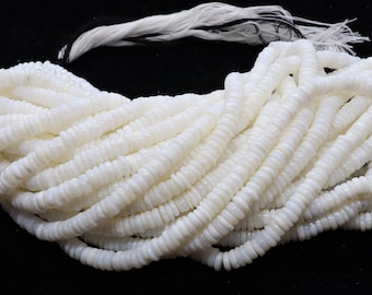 May include: A strand of white shell beads, each bead is a flat, round disc with a slightly raised center. The beads are strung on a white cord.