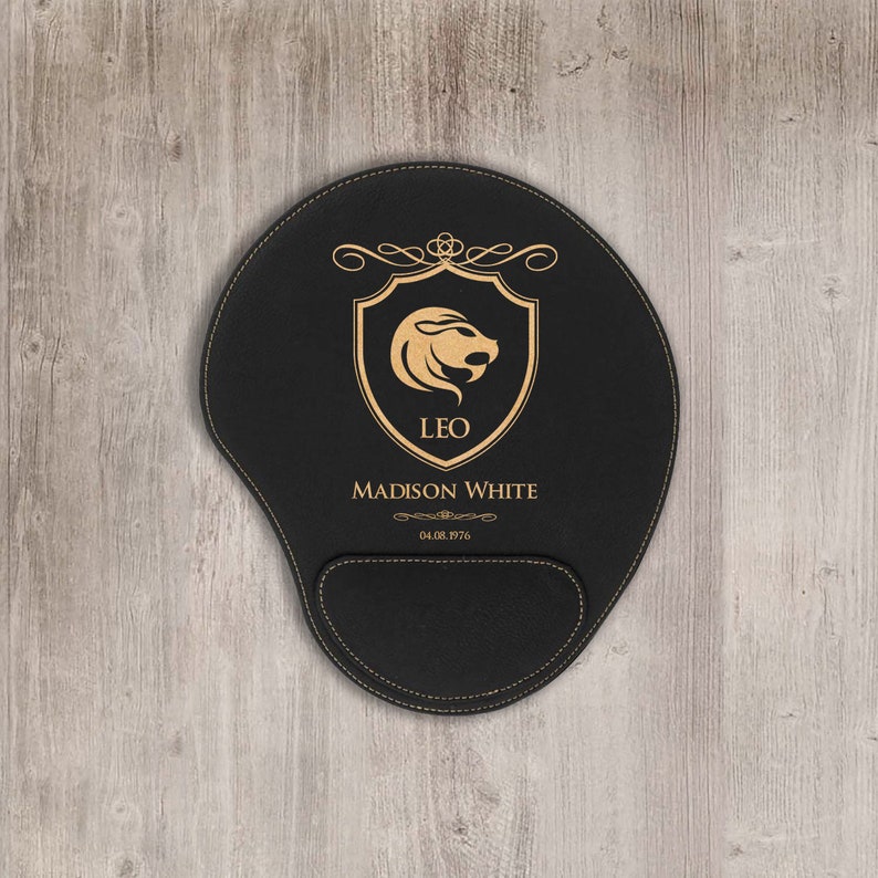 a mouse pad with wrist rest support made from a faux-leather material laser print name, and zodiac in gold color on a black color background