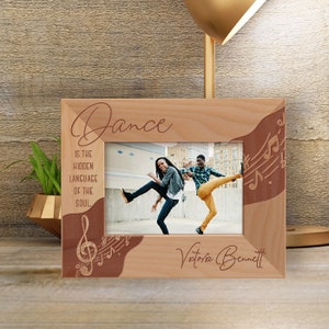 May include: A wooden photo frame with a brown and white design. The frame has a quote about dance and musical notes. The frame is personalized with the name "Victoria Bennett".