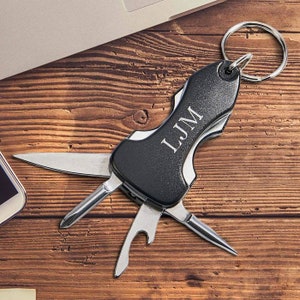May include: Black multi-tool keychain with a silver blade and bottle opener. The keychain has the initials "LJM" engraved on the handle.