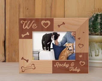 May include: A wooden photo frame with a brown and natural wood finish. The frame has a cutout design of hearts, bones, and the words "We" and "Rocky & Toby".