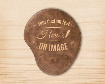 May include: Brown leather mouse pad with a stitched edge. The pad has a raised area for the wrist. The text "Your Custom Text Here OR IMAGE" is engraved on the pad.