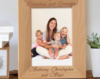 May include: A wooden picture frame with a photo of a woman and three children. The frame is engraved with the text "We Love You, Grandma and Grandpa!" and "Anthony, Christopher and Alexis".