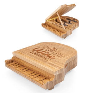 May include: A wooden piano-shaped cheese board with a cutting surface and a built-in drawer for cheese knives. The board is engraved with the words "Wine Collection" and "Alexander".