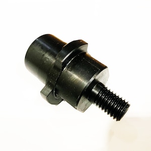 May include: Black metal adapter with a threaded end and a hexagonal shape. The adapter is designed to connect two different sized pipes or fittings.