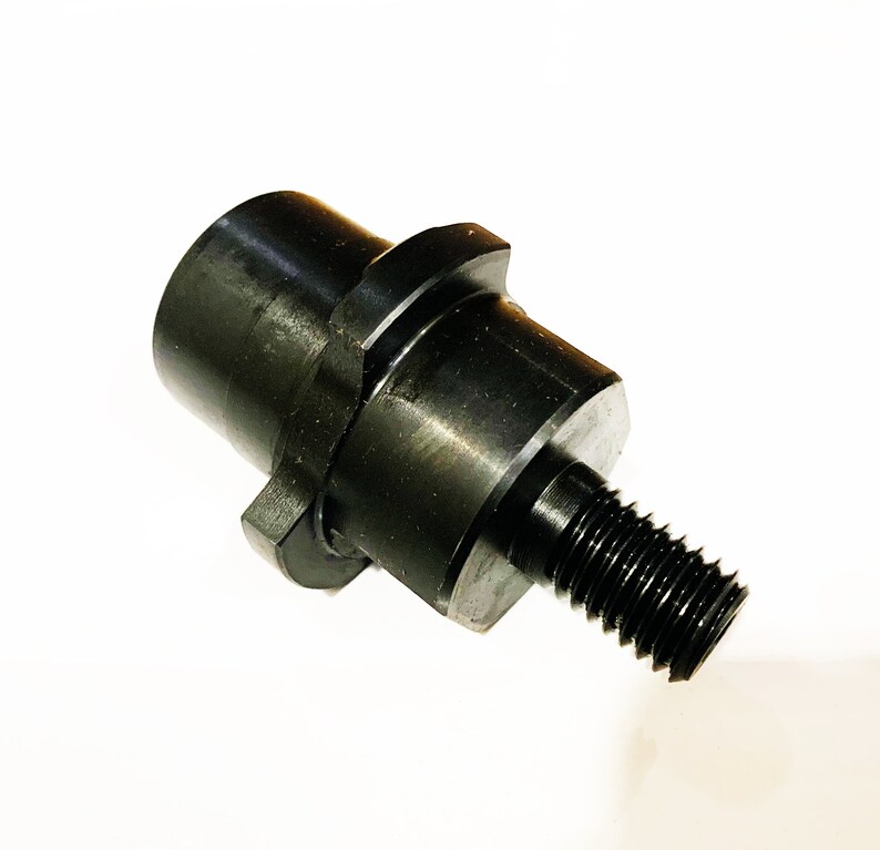 May include: Black metal adapter with a threaded end and a hexagonal shape. The adapter is designed to connect two different sized pipes or fittings.