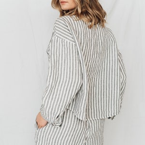 May include: A striped linen shirt and shorts set in a white and gray color scheme. The shirt has a relaxed fit and the shorts have a mid-thigh length.