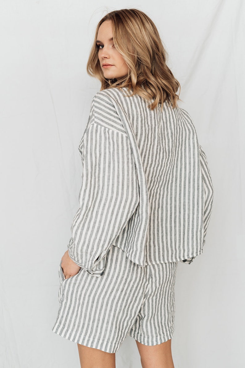 May include: A striped linen shirt and shorts set in a white and gray color scheme. The shirt has a relaxed fit and the shorts have a mid-thigh length.