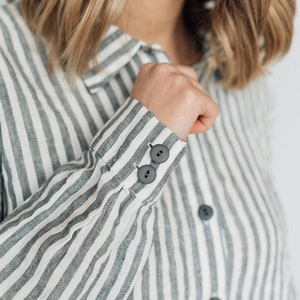 May include: A striped linen shirt with a button-up collar and long sleeves. The shirt has a relaxed fit and features two buttons on each cuff.