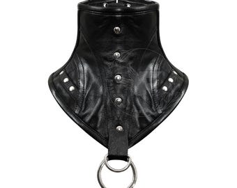 May include: Black leather choker with silver studs and a metal ring. The choker has a pointed shape and is designed to be worn around the neck.