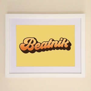 May include: A framed print with a yellow background and the word "Beatnik" written in a retro, orange and brown font.