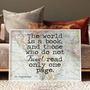 May include: A rectangular wall art print featuring a vintage-style world map background with the black text: The world is a book, and those who do not travel read only one page. St. Augustine. The map displays muted colours of green, blue, and tan.