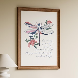 May include: A framed wall art print featuring a stylized dragonfly with pink, blue, and white wings, surrounded by floral accents. Below the dragonfly, cursive text reads: Sing me a song of a lass that is gone, Say, could that lass be I? Merry of soul she sailed on a day over the sea to Skye.