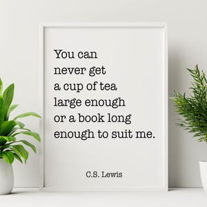 以下が含まれることがあります： C.S. Lewisによる「You can never get a cup of tea large enough or a book long enough to suit me.」という引用句が書かれた白いフレームのプリント。白い表面にあり、両側に緑の植物が配置されています。