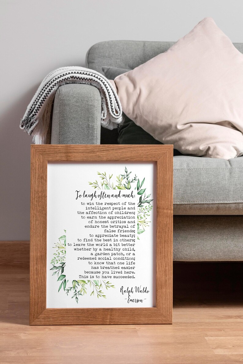 May include: A framed print with a white background and green floral accents. The print features a quote by Ralph Waldo Emerson: "To laugh often and much... This is to have succeeded."