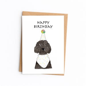Puede incluir: Tarjeta de cumpleaños con un perro negro que lleva un gorro de fiesta y un pañuelo con lunares de colores. Las palabras "HAPPY BIRTHDAY" están impresas encima de la cabeza del perro en letras negras. La tarjeta está dentro de un sobre marrón.