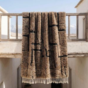 Chocolate brown rug hand tufted in Morocco from 100% natural wool, featuring a plush high pile with subtle black geometric texture. This solid brown wool rug showcases earthy tones and a minimalist Berber-inspired design, finished with soft fringe. Ideal as a warm modern area rug for Scandinavian, boho, or earthy interior spaces