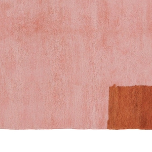 K&ouml;nnte beinhalten: Ein rosa-brauner Teppich mit Fransenrand. Der Teppich hat ein geometrisches Design mit einem einfarbigen rosa Abschnitt und einem braunen Rechteck.